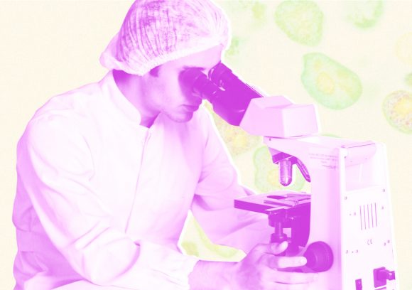 Person wearing hairnet looking through a microscope.