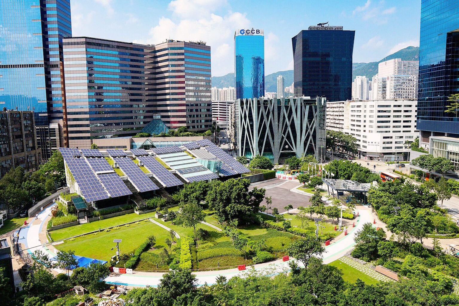 View of a city with tall buildings and large amounts of green space and solar panels.