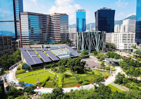 View of a city with tall buildings and large amounts of green space and solar panels.