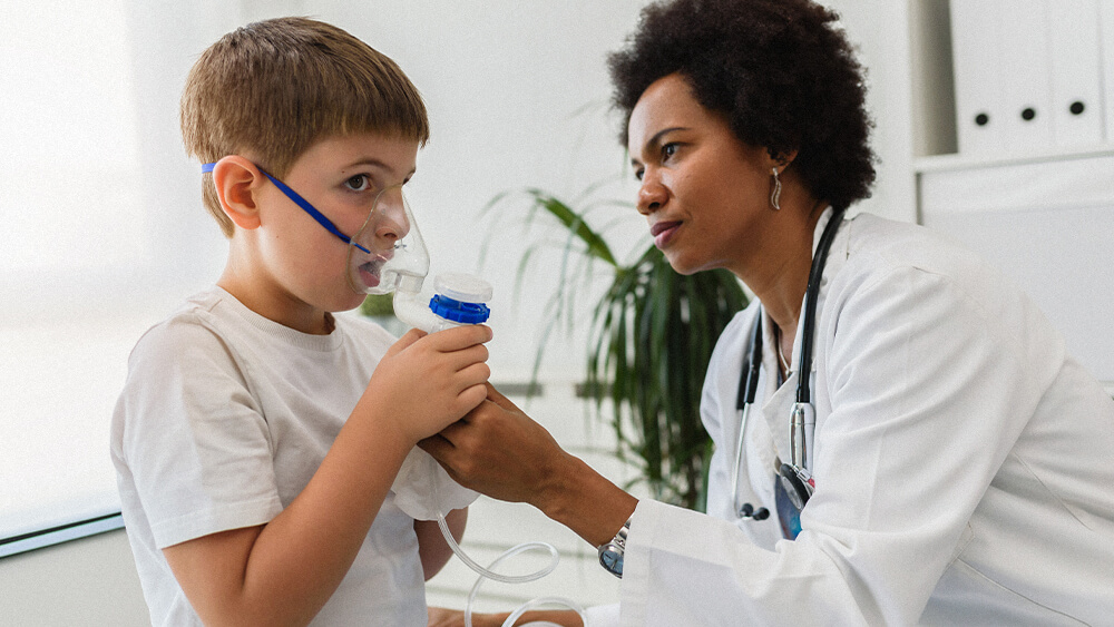 Respiratory therapist working with young patient who is using a nebulizer.