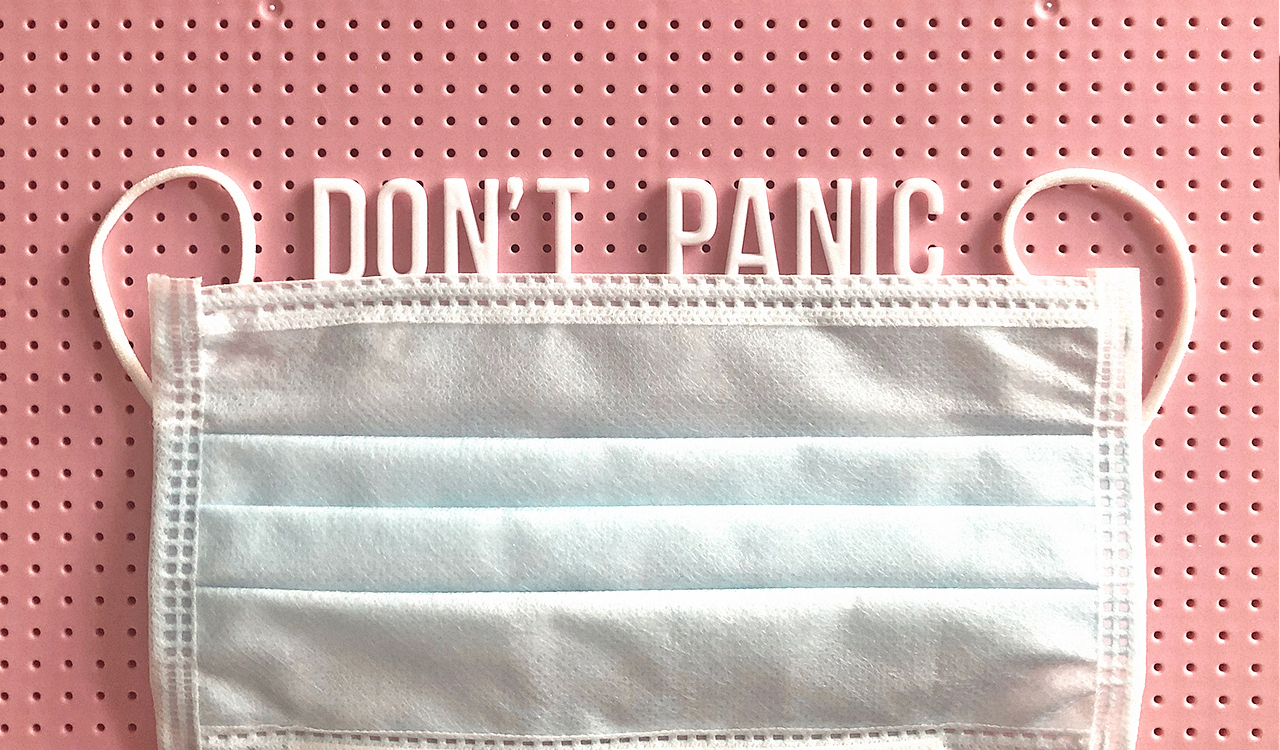 Pink pegboard with a mask and the words 'don't panic.'