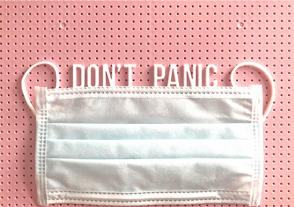 Pink pegboard with a mask and the words 'don't panic.'