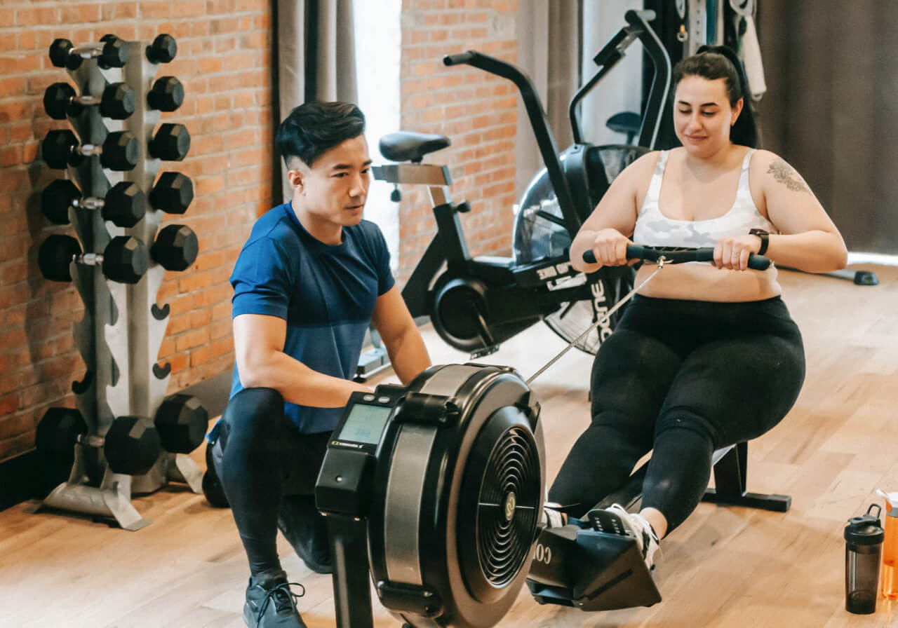 A person trainer works with a client on a rowing machine.