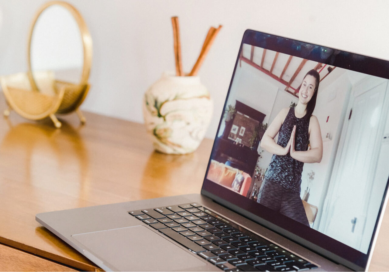 A computer with someone demonstrating yoga poses during an online class.