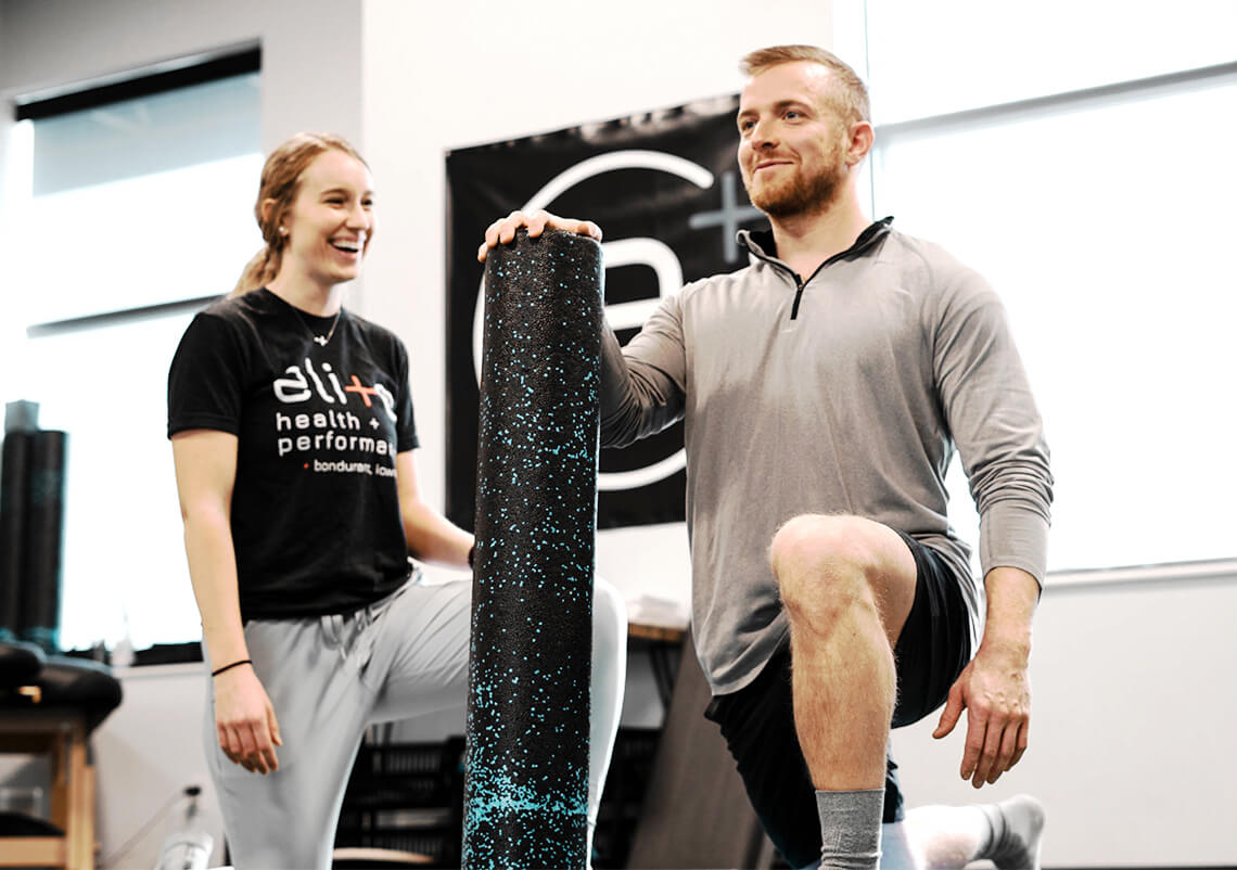 Personal trainer working with a client while using a foam roller.