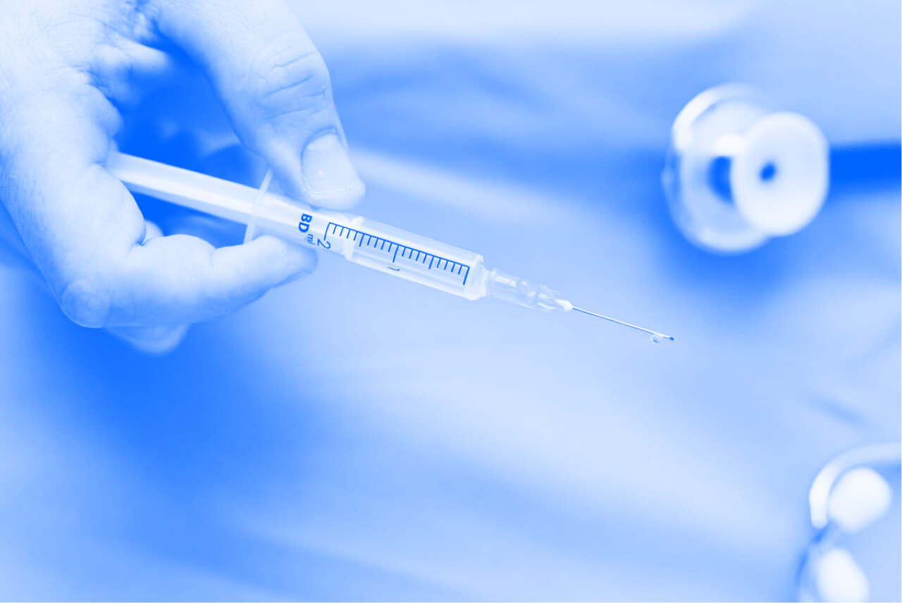 A person holding a hypodermic needled. Blue-tinted close up.