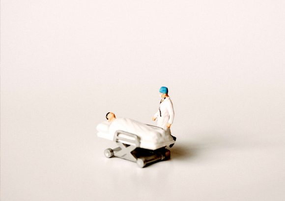 Miniature figurine of patient and nurse on white background.