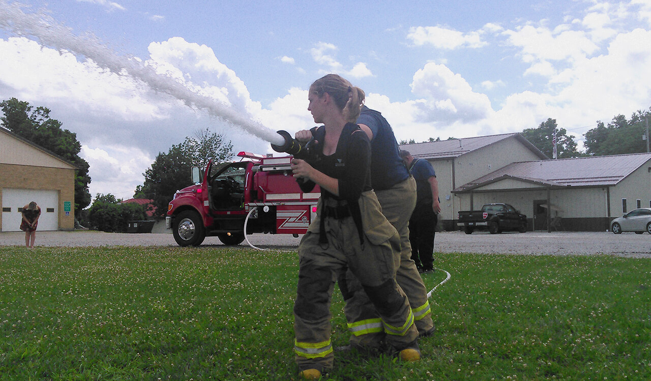 Lakota holding a fire hose during firefighter training.