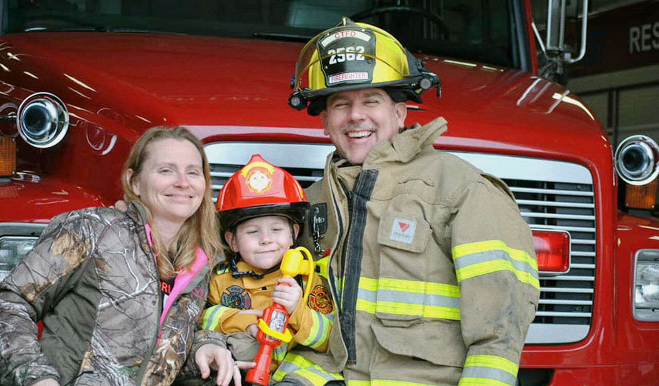 Todd May in a firefighter uniform with his family.