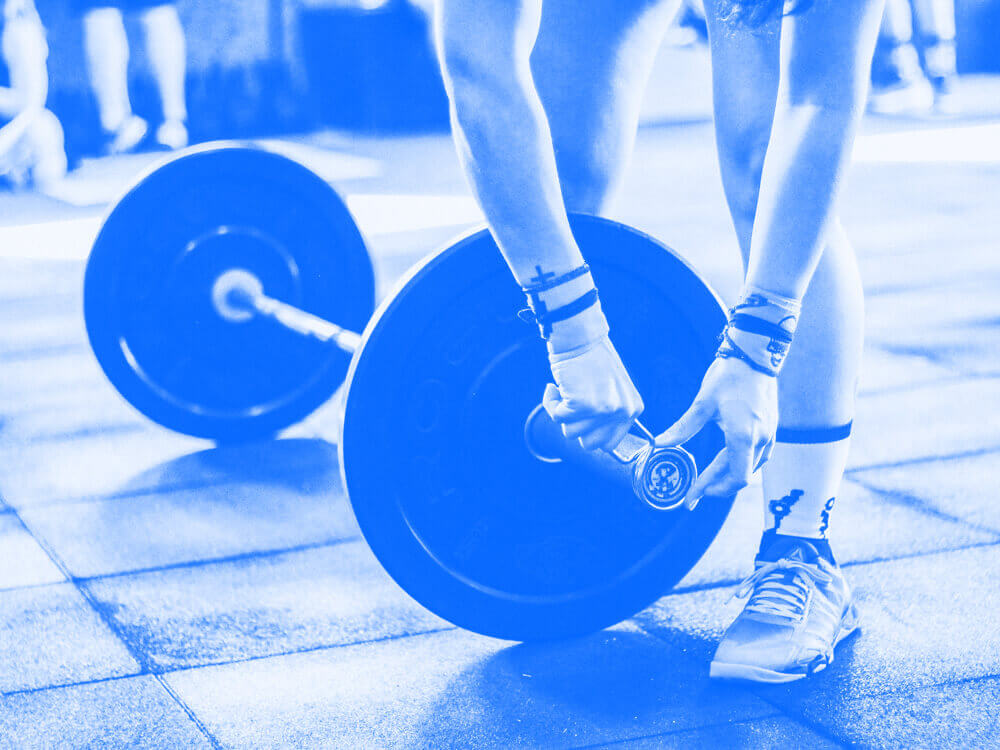 Person securing a weight plate at one end of a deadlift bar.