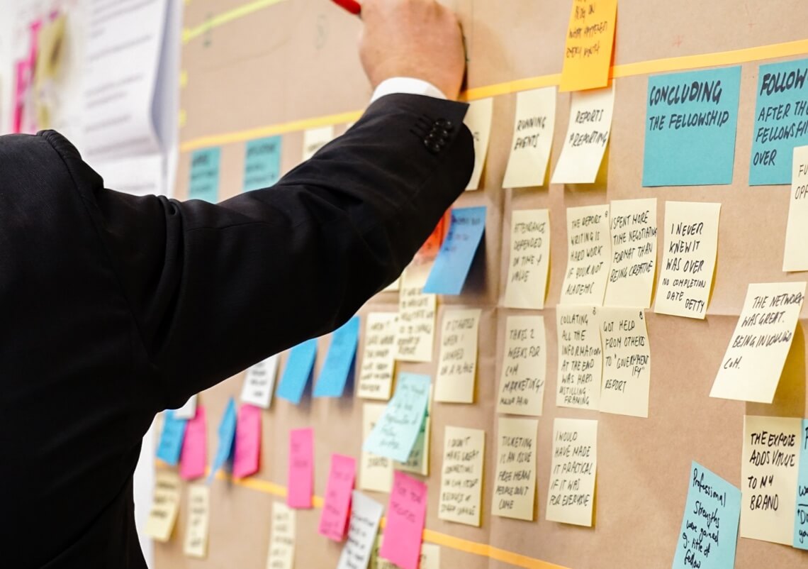 A project manager works on organizing a board with sticky notes.