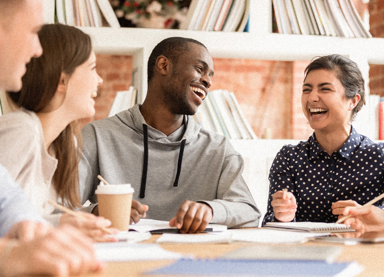 A group of people studying together at a table and laughing.