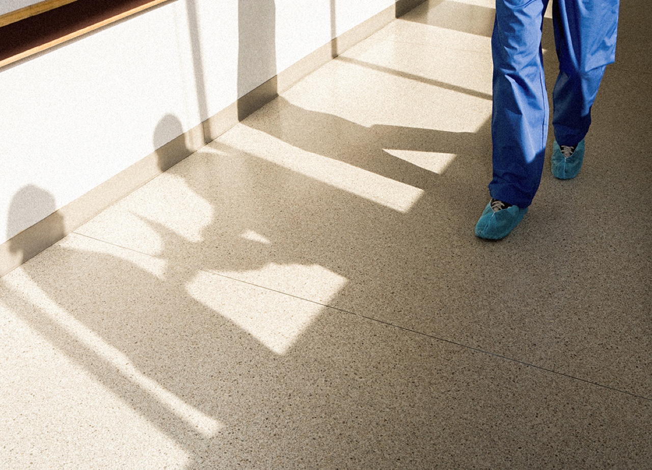 A CRNA walks down a sunlit hall. Closeup of feet.