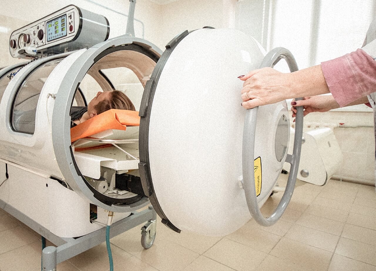 A nurse closes a patient into a hyperbaric chamber.