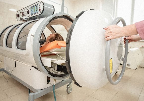 A nurse closes a patient into a hyperbaric chamber.