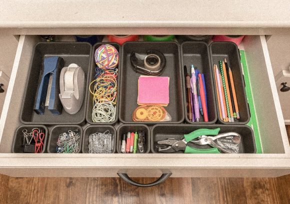 An open drawer showing different office supply items neatly organized in black trays.
