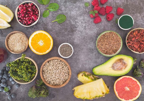 Top-down view of healthy foods, including nuts, avocado, and grapefruit, on a slate countertop.