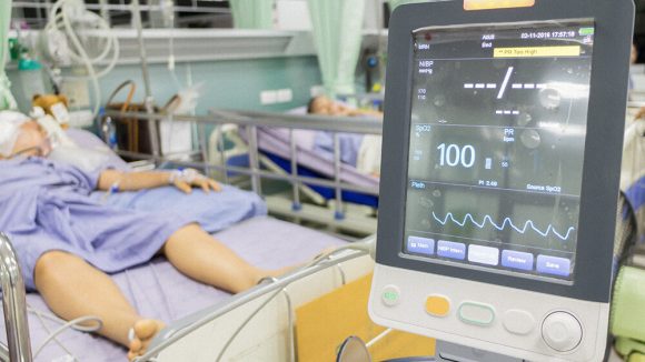Patient laying in hospital bed connected to a monitor that is displaying their vitals.