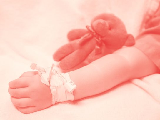 Child's arm with IV in a hospital bed.