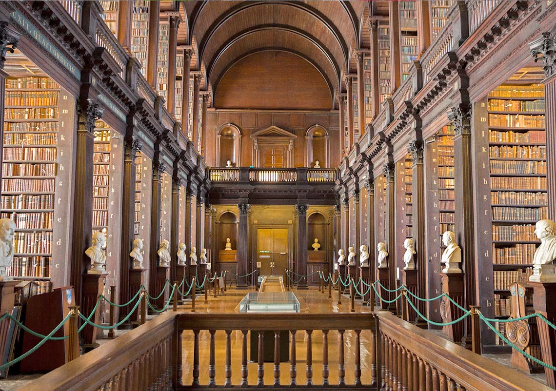 A large prestigious library with many books, arches, and white marble busts.
