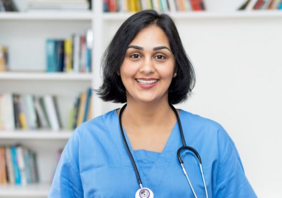 Certified nurse educator smiling while wearing blue scrubs and a stethoscope.