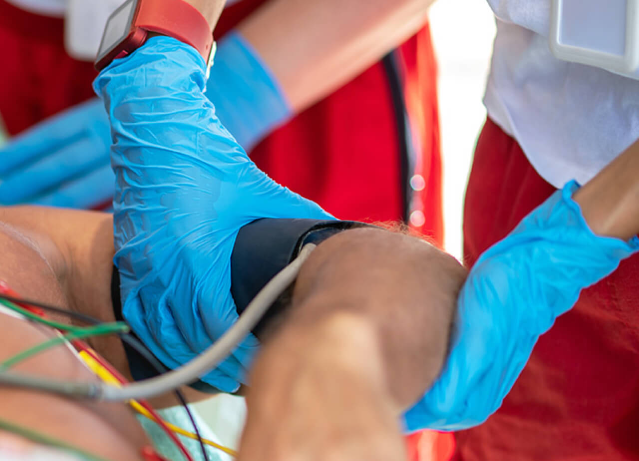 Close up of an advance emergency technician fixing a blood pressure cuff over a patient's upper arm.