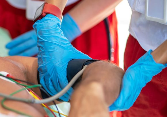 Close up of an advance emergency technician fixing a blood pressure cuff over a patient's upper arm.