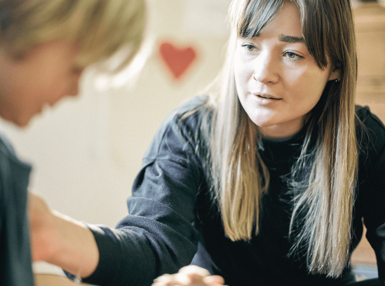 A Registered Behavior Technician attentively engages with a young child in a calm, supportive setting.