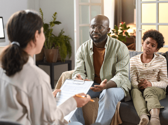 A therapist speaks with a man and a child during a family counseling session