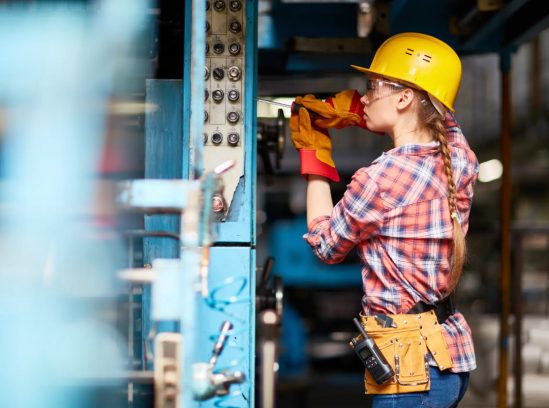 Woman in a hard hat using a drill